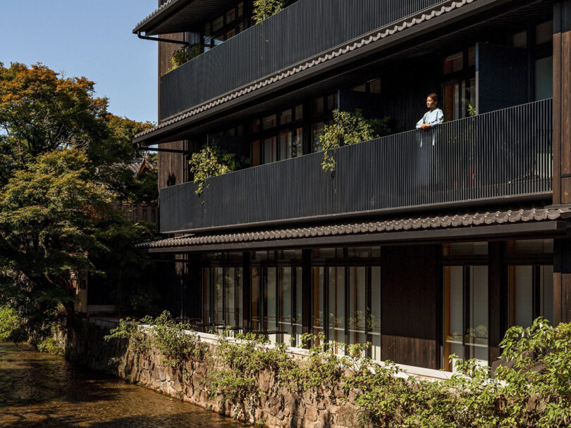 Woman standing on balcony overlooking a river in Kyoto.