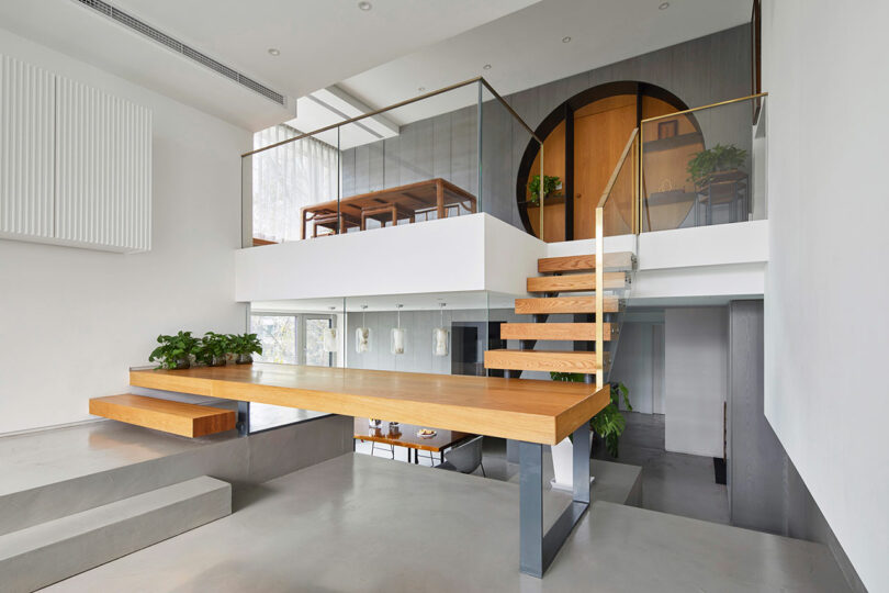 angled living room view showing unique sculptural floating staircase leading to mezzanine level