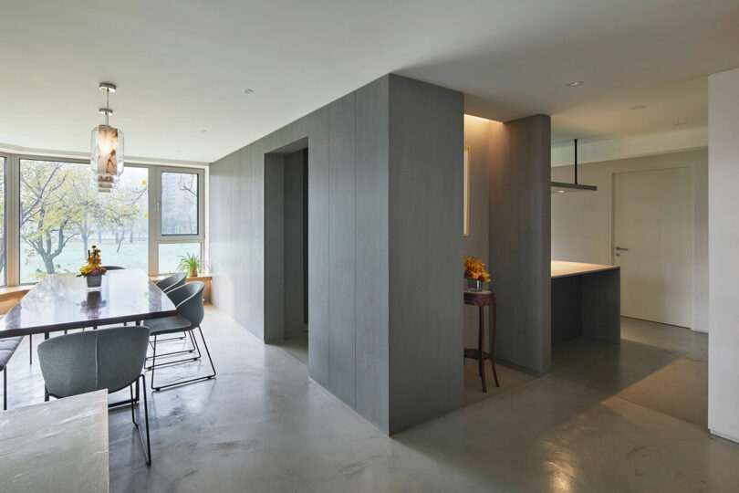 angled interior view of dining table and gray built-in block housing utilities and the kitchen