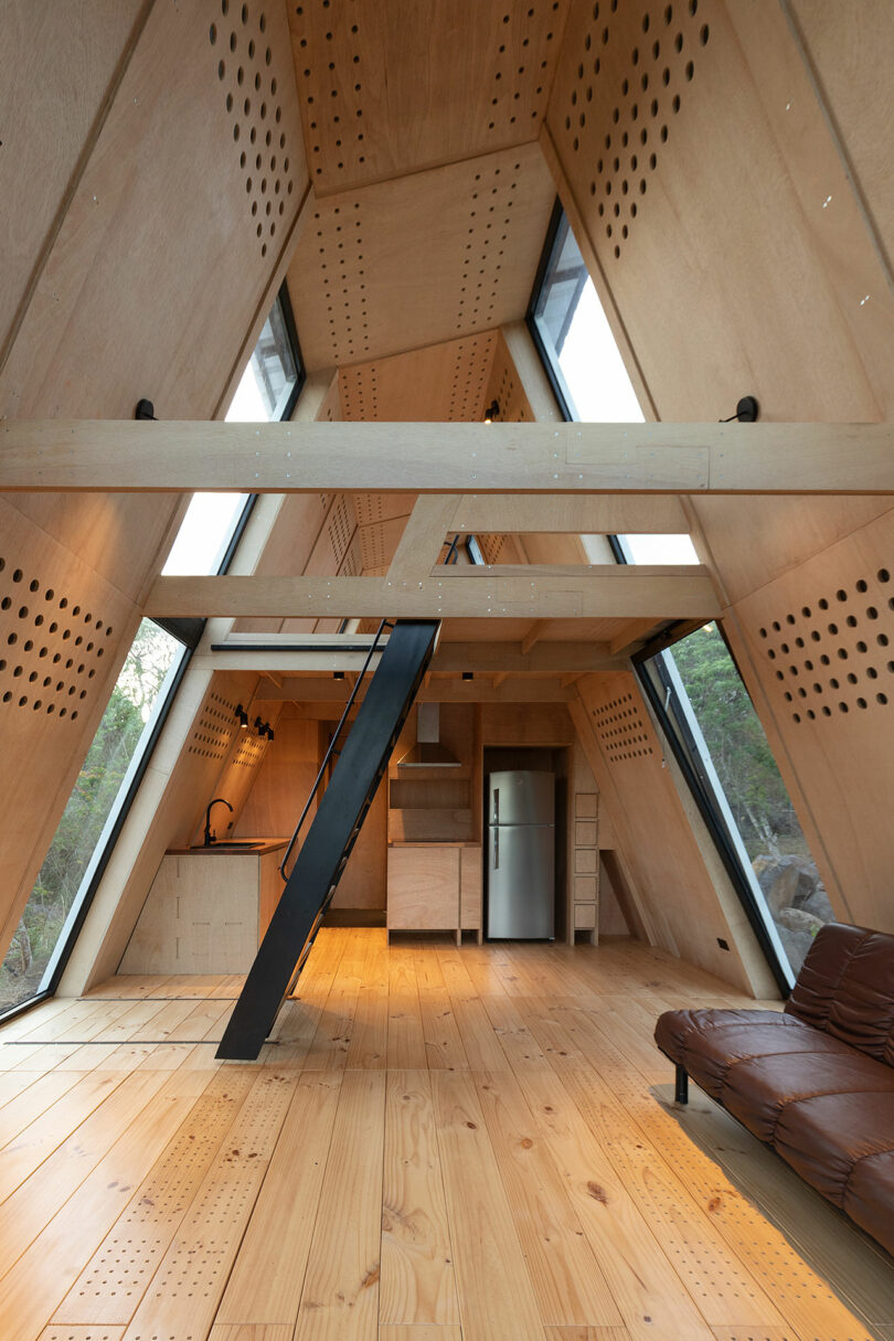 long interior view of modern cabin with slanted wood walls and minimalist decor