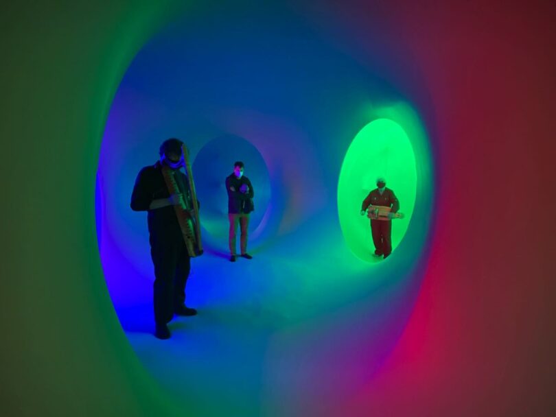 Inside of Colourscape Music Festival, 3 musicans playing instruments in a colorful chamber