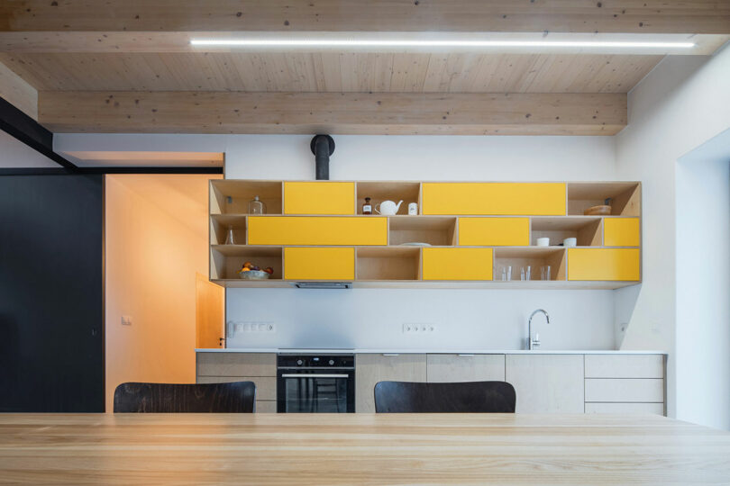 view in modern kitchen with wood cabinets and yellow and wood upper cabinets