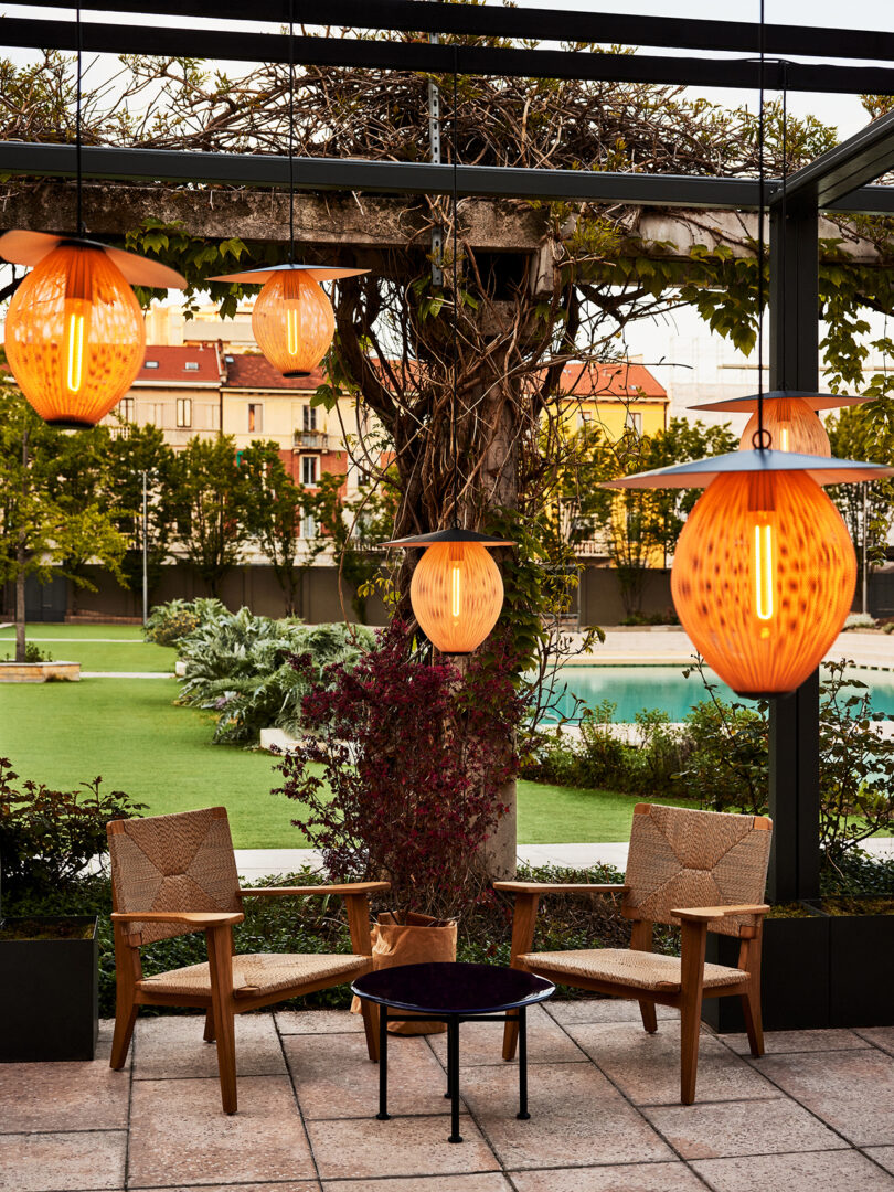 neutral toned outdoor seating area with two armchairs and several illuminated hanging light fixtures