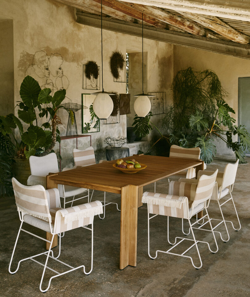 neutral toned outdoor dining space with dining table and six chairs and two hanging light fixtures