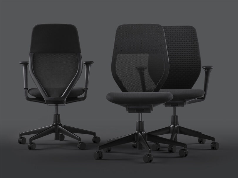 Three all-black Vitra ACX task chairs with mesh and knit woven backs. The first chair on the left is with its back facing toward viewer, other two on the right are facing forward. All three have caster wheels.