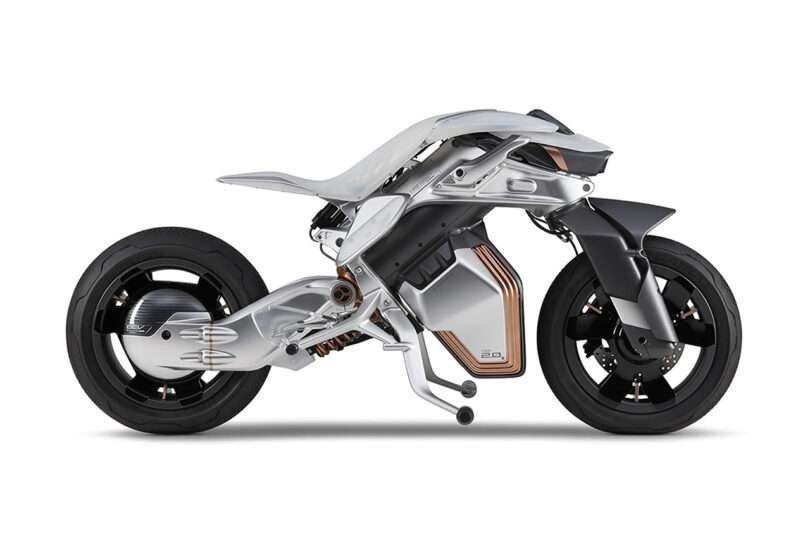 Side parked view of the Yamaha MOTOROiD 2 electric motorcycle concept, a bike with an independently pivoting front and back section. A battery compartment sits near the front wheels, with two prong kickstands underneath.