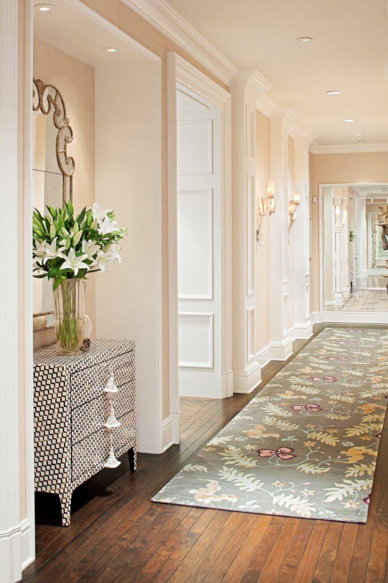 Entryway with a rug runner, featuring a table with mirror and a plant.