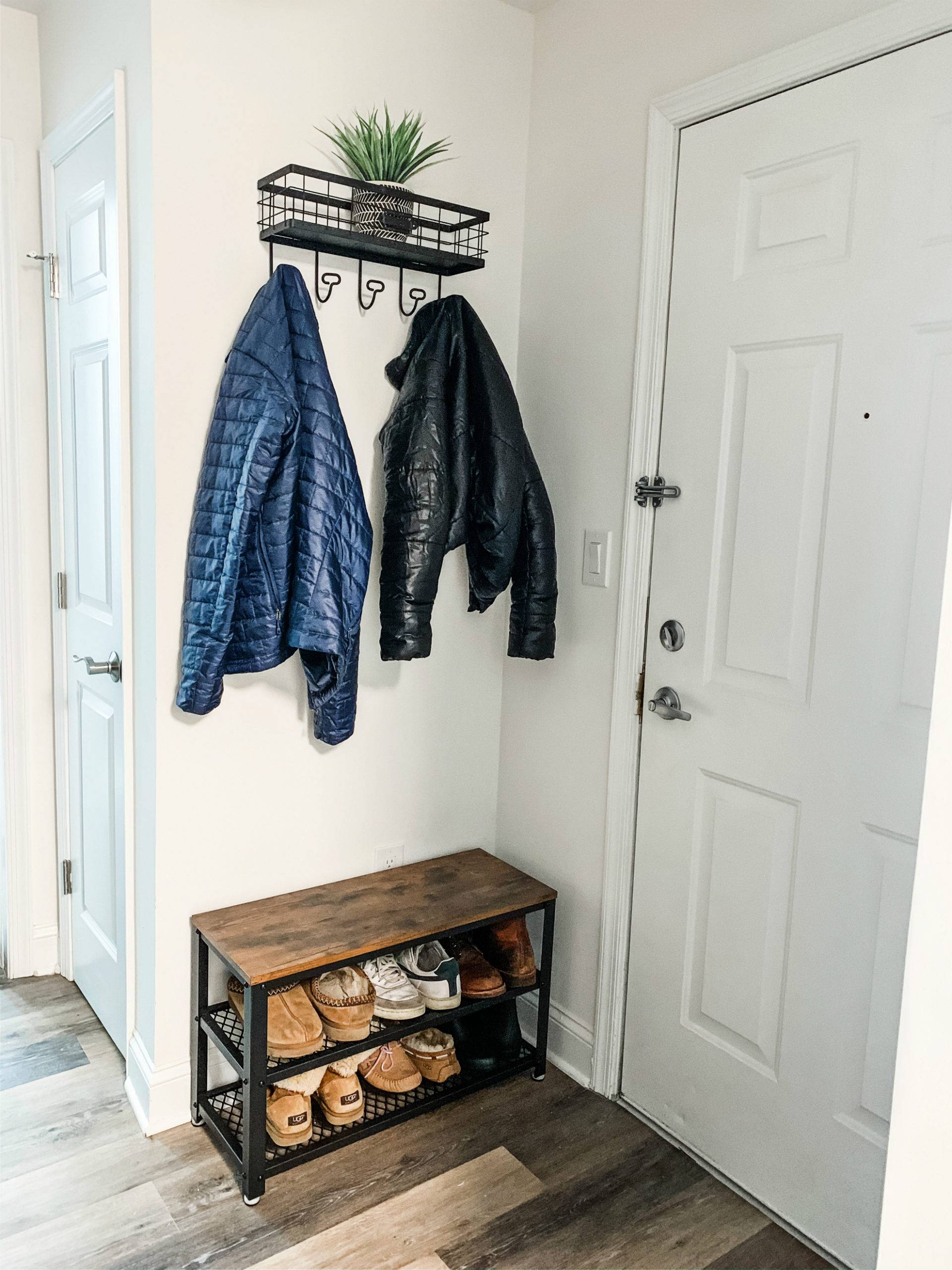 Entryway with a small bench that doubles as shoe storage with coat hung above it.