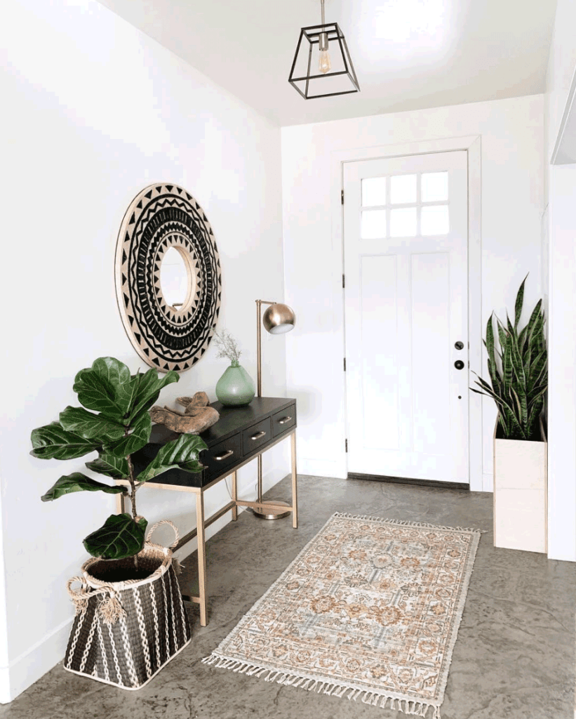 White entryway with a circular mirror, plants, and a table.