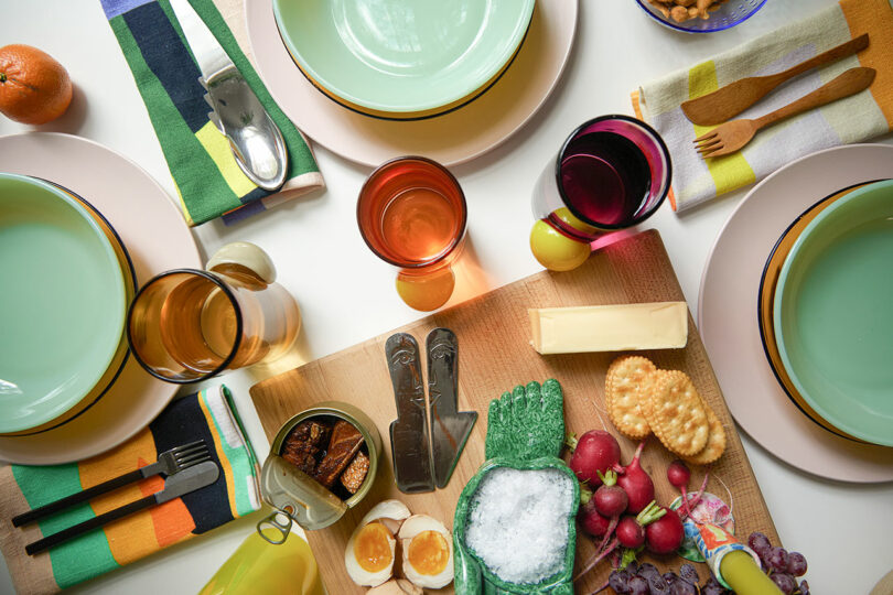 overhead image of a table setting with plates, glasses, utensils, and colorful fabric napkins