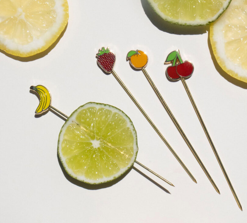 four cocktail picks with fruit shapes on the end of each