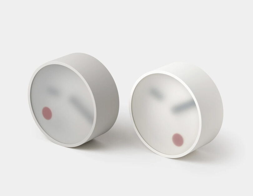 Two modern clocks with a semi-translucent clock face with red dot and arms