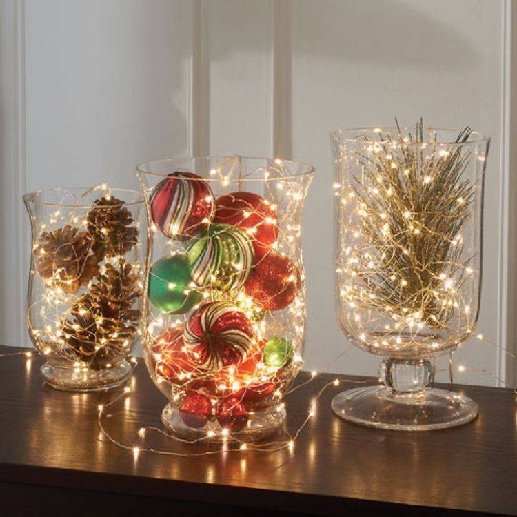 large hurricane jars with christmas lights pinecones and ornaments