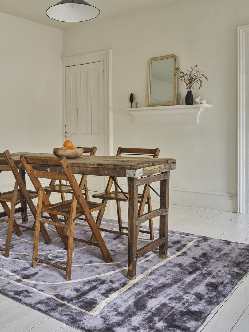 dining table and four chairs on top of an abstract rectangular rug