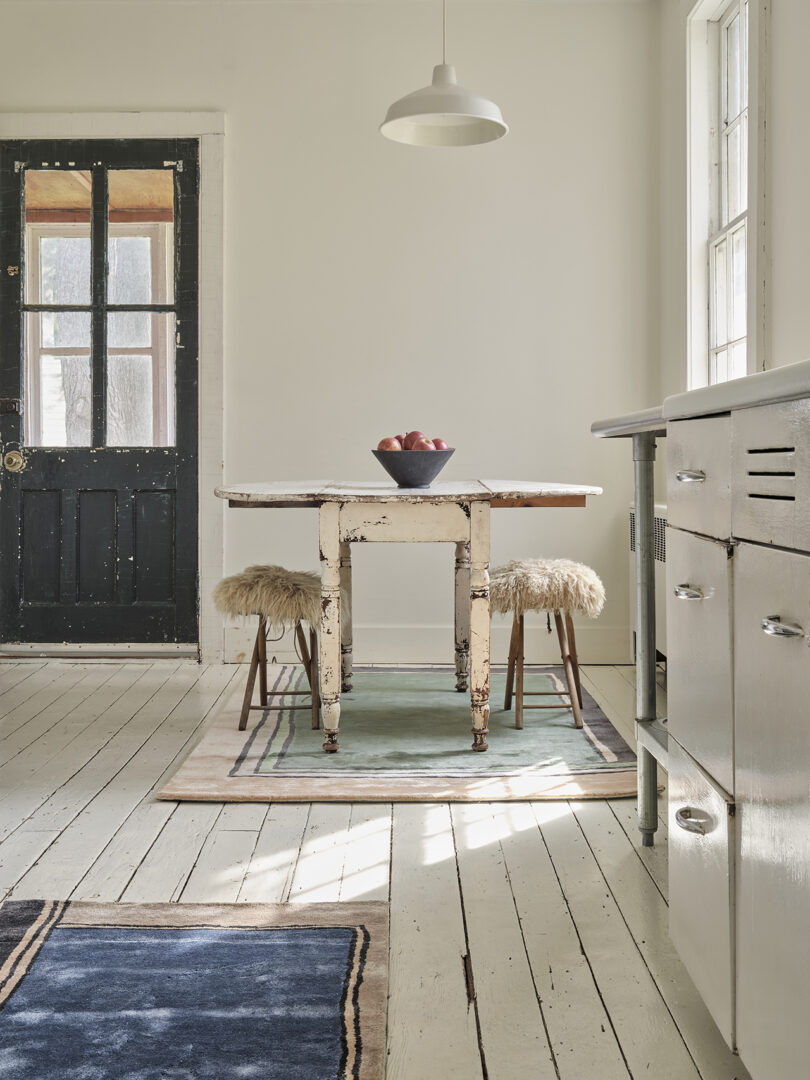 kitchen table and two stools on top of an abstract rectangular rug