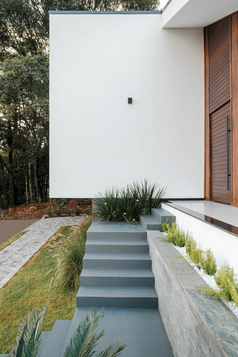 side partial view of modern house with gray stairs leading to entrance