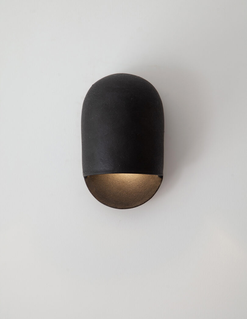 black domed ceramic sconces hanging on a white wall
