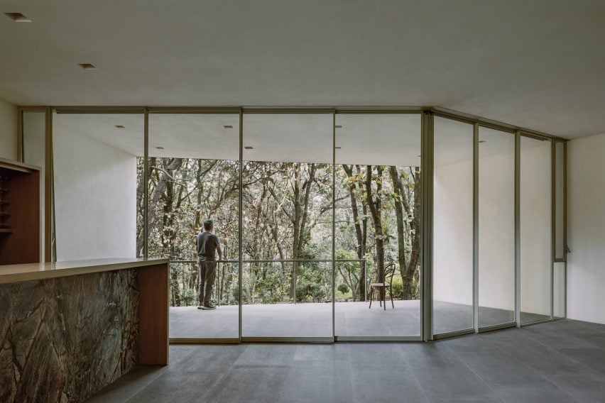 Large windows in an open-plan kitchen overlooking a forest