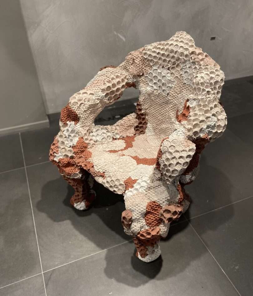 A sculptural chair is indented with circles and features blobs of colour in off white, pale pink and terracotta.