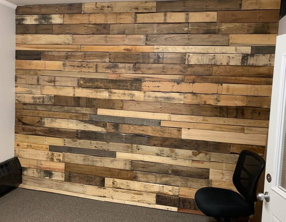 Pallet accent wall and a black office chair.