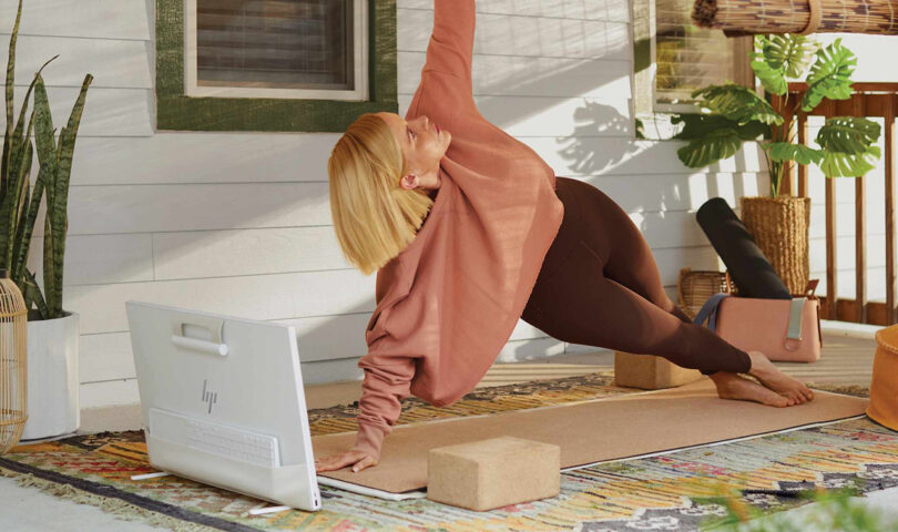 Woman in side plank pose with HP Envy Move PC in front of her following instructions on the screen.