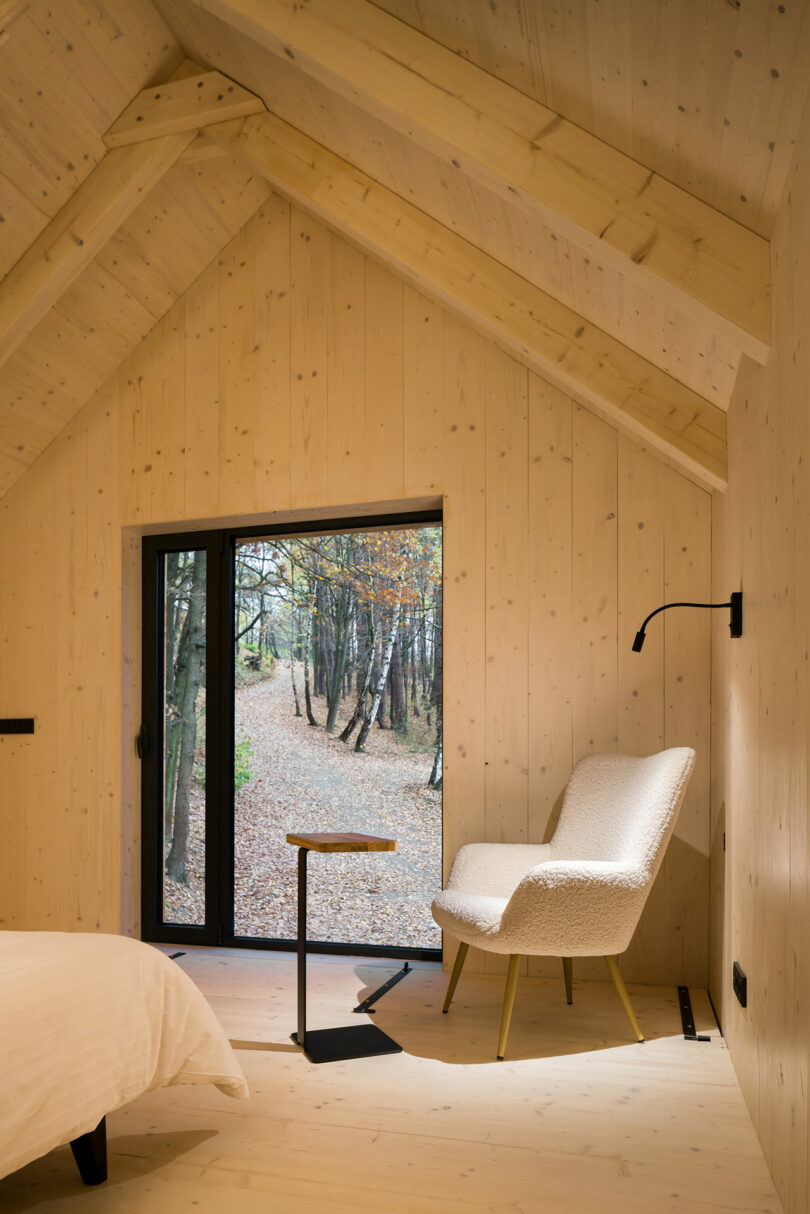 angled view of minimalist bedroom with light wood walls looking out through window