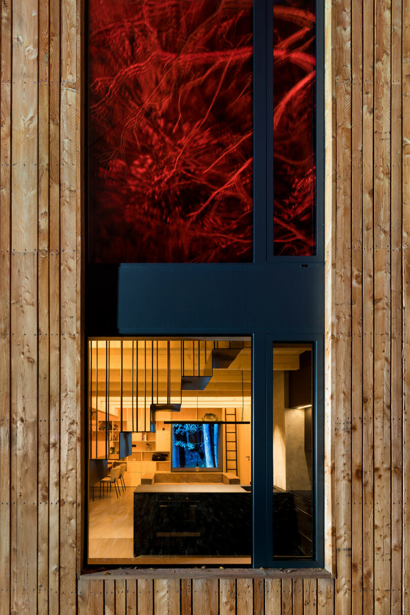 closeup partial night view of modern wood cabin in woods with red lights shining on surrounding trees