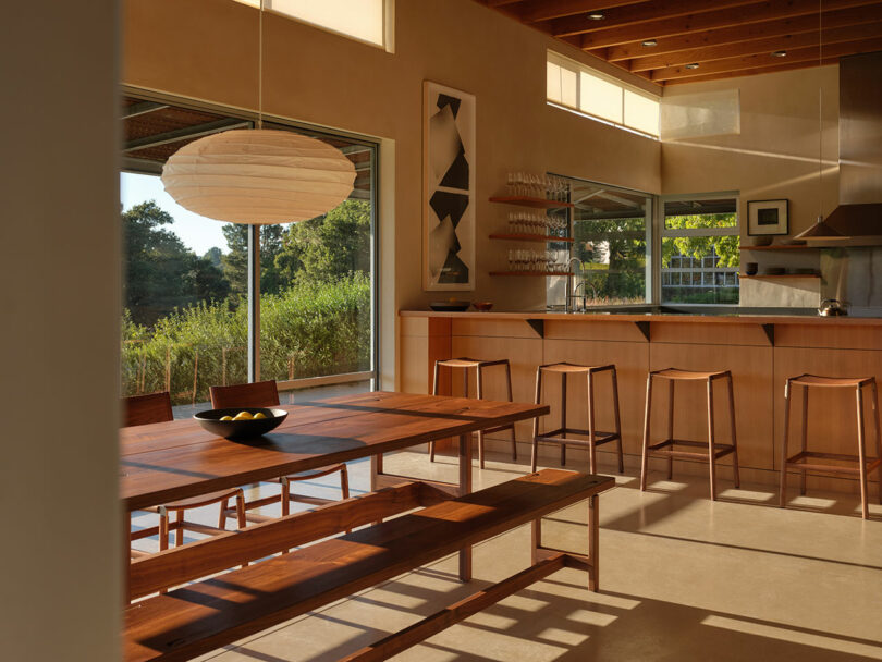 Angle shot of kitchen and dining space with table, bench, and chairs.