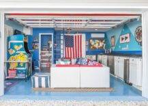 Converted garage man cave features a vintage arcade Ms. Pac-Man game in front of a white wicker sectional with red seat cushions and a matching coffee table. Blue walls, beadboard cabinets, and gray countertops include a kitchenette in the converted man cave space.