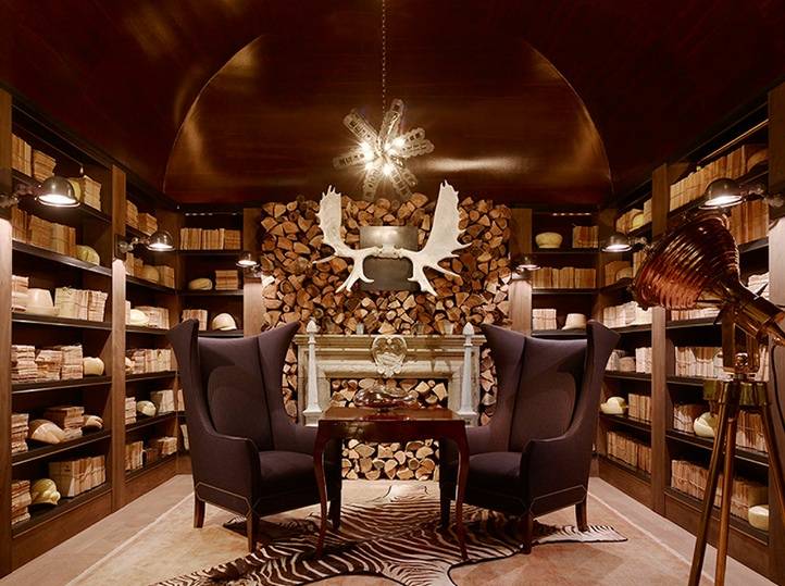 Amazing den with wood barrel ceiling built-in bookcases, stone fireplace, zebra cowhide rug and black linen wingback chairs with silver nailhead trim.