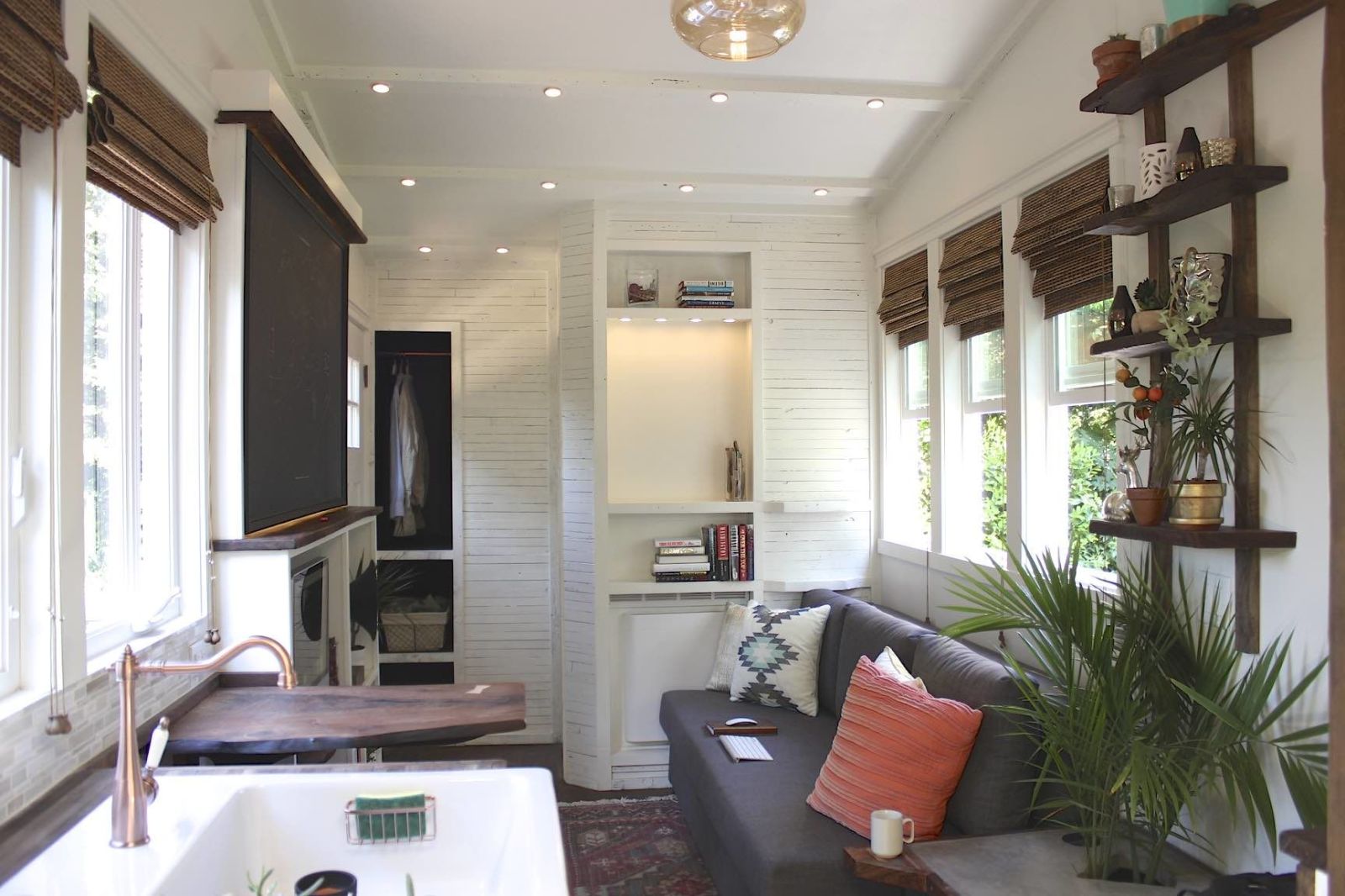 White minimalistic tiny home with natural color decor and pod ceiling lights.