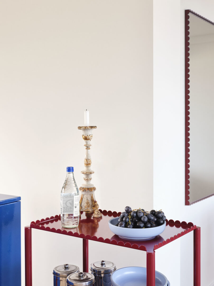 candle stick, bottle of water, and bowl of fruit on burgundy trolley
