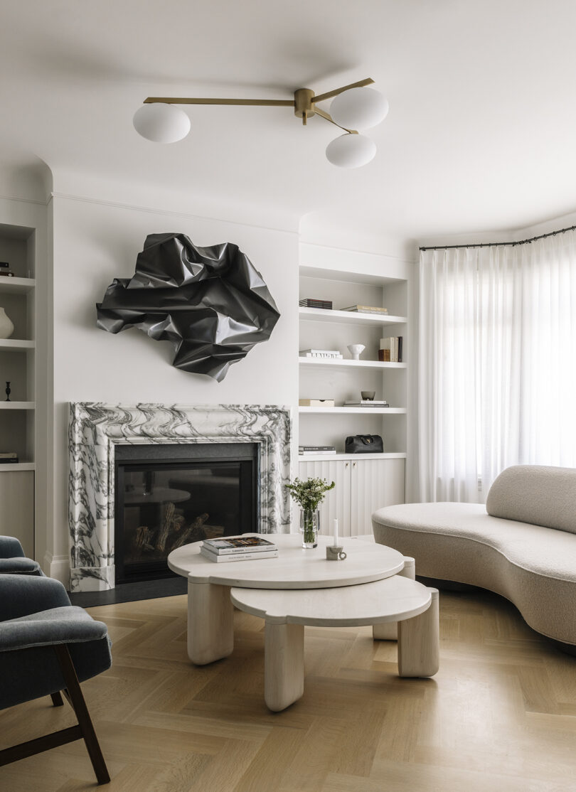 light and bright styled interior living spae with white sofa, armchair, double coffee table, and fireplace