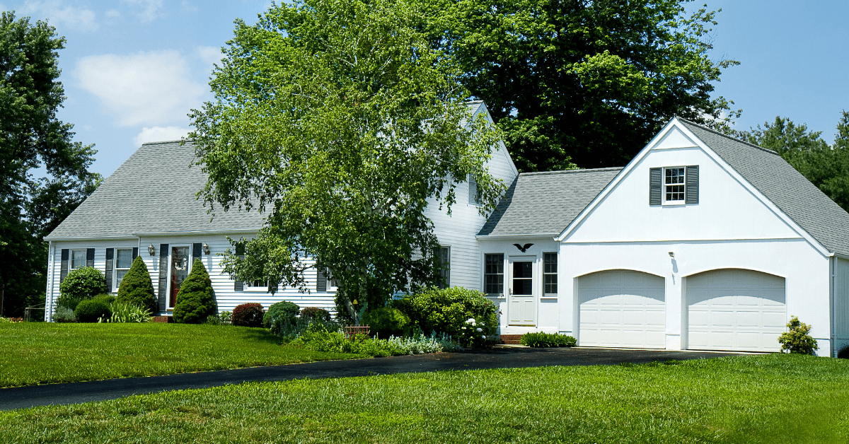 Large Cape Cod house with double door garage attached through an extension.