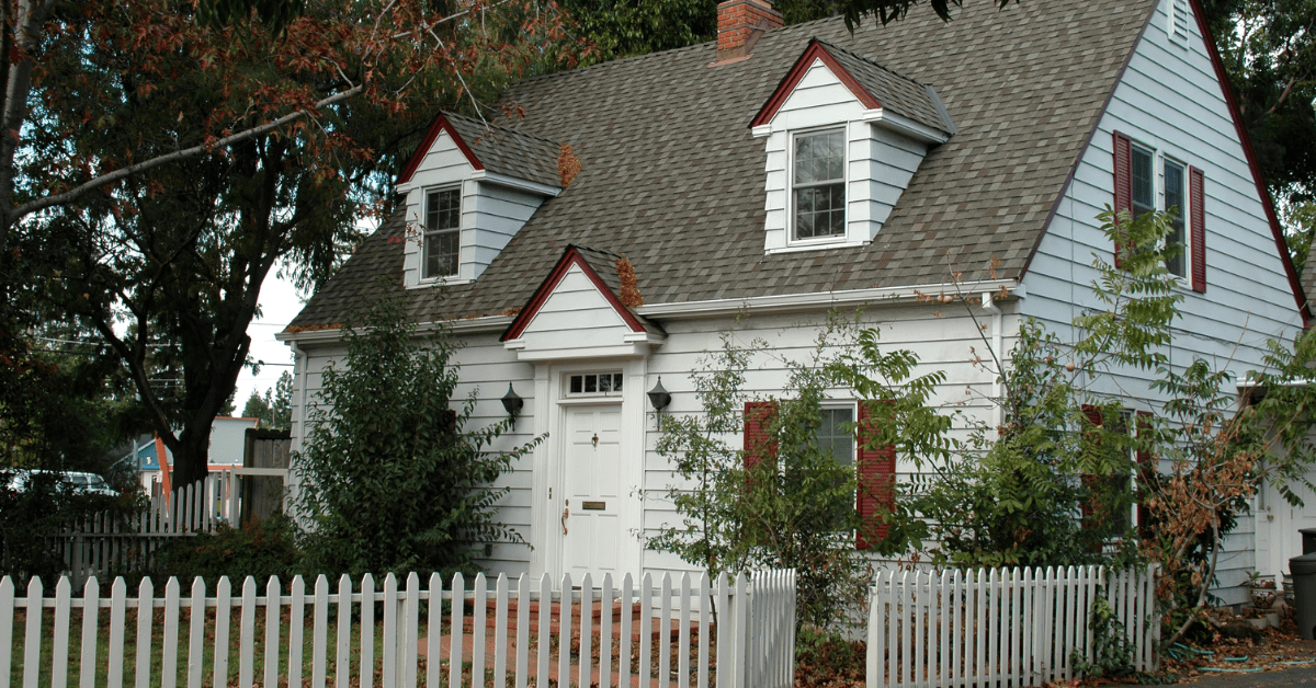 Cape Cod style house with white fencing.