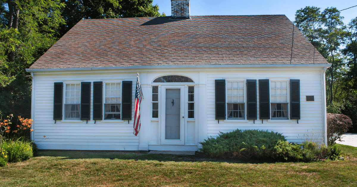 Small Cape Code house with America flag mounted by the front door.