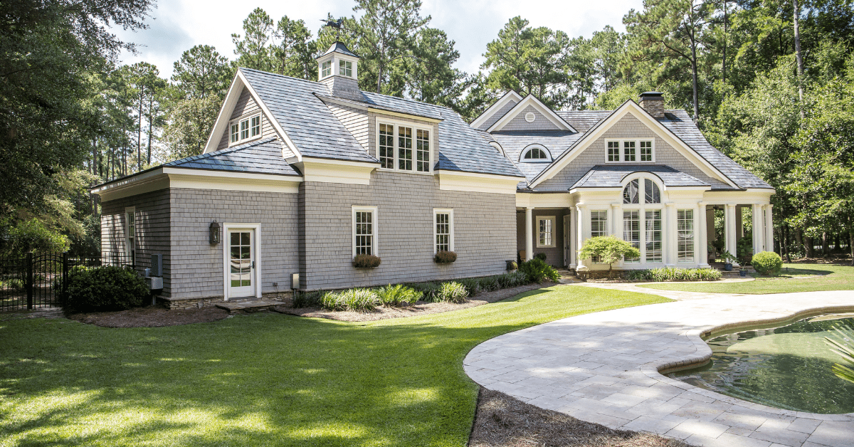 Large Cape Cod house with concrete walk way.