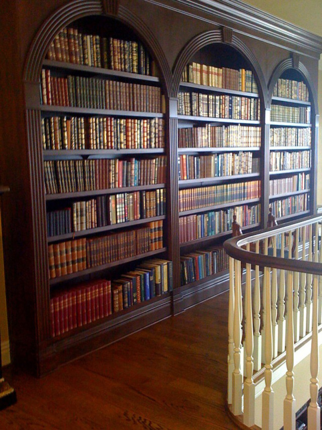 A wooden staircase leads to a hallway with a bookcase. The staircase leads upwards, while the bookcase stands as a focal point.