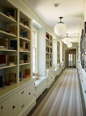 Long hallway with multiple bookshelves and a striped rug.