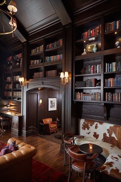 A library adorned with plush leather couches and lined with shelves filled with books.