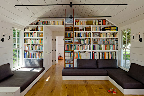 Living room featuring grey couches and large bookshelves.