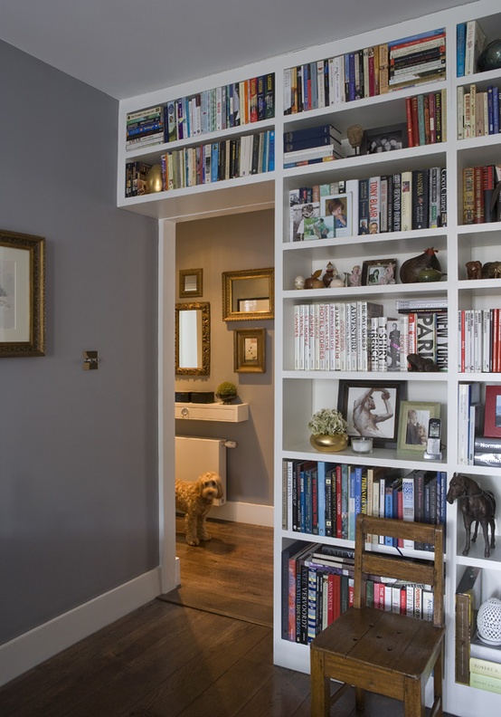 A bookcase filled with numerous books fronted by a wooden chair.