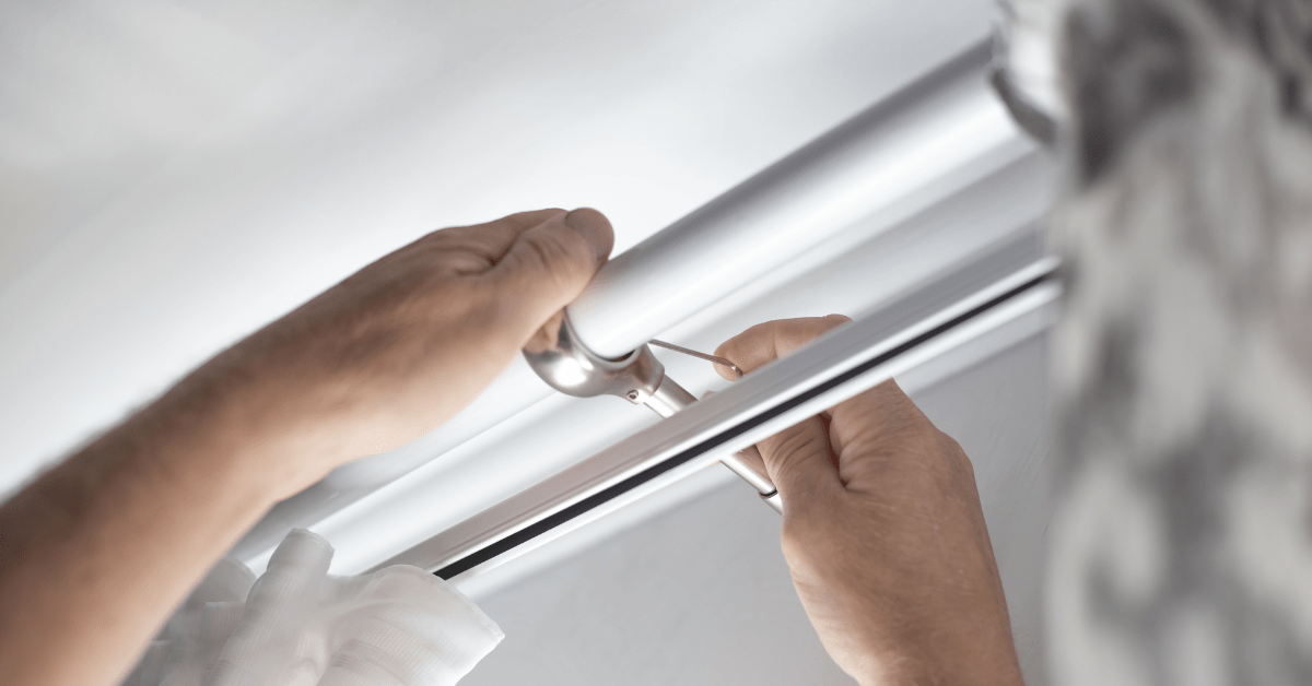 Person's hands securing curtains rods.