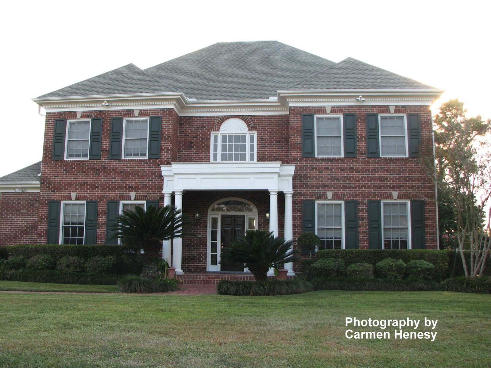 Dark red brick house with white trim and multiple large windows.