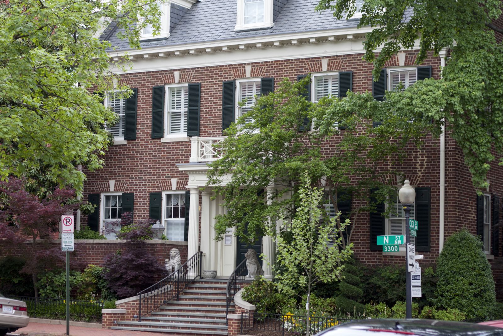 Red brick house with stairs leading to the front white door.