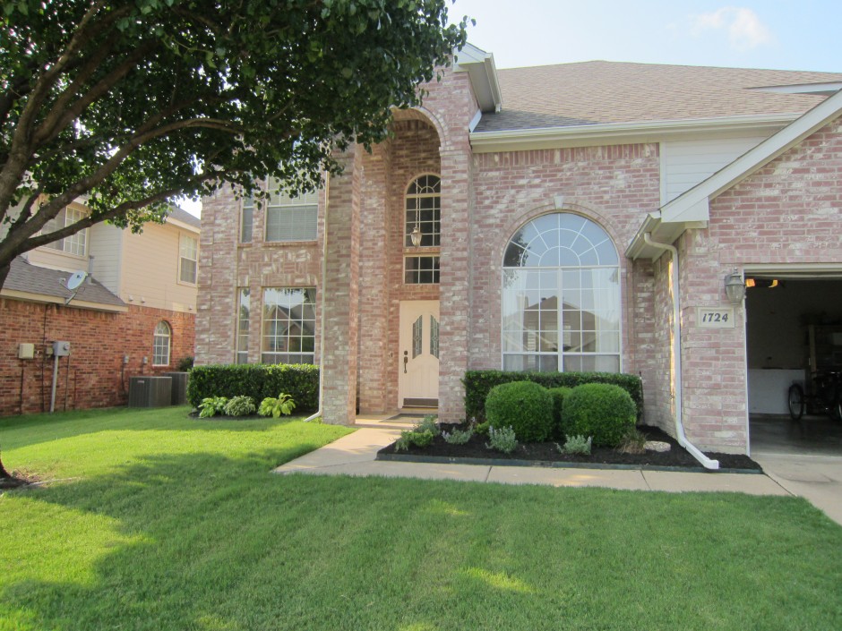 Cream-colored red brick house with white fixtures and a large window upfront.