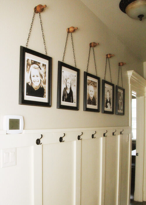 Picture gallery in a white hallway, hanging four pictures.