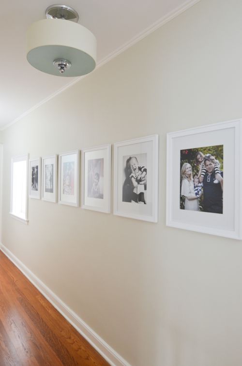 Hallway gallery with large white framed family pictures.
