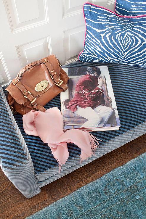 Placed on a blue overdyed rug, a black and blue velvet settee is complemented with blue animal print pillows positioned against a wall clad in millwork.