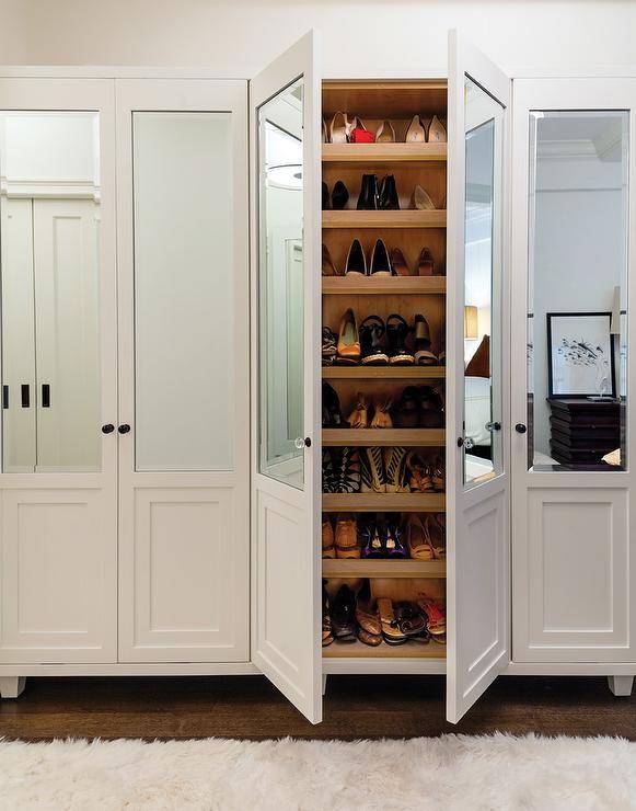 Glam walk-in closet boasts a wall of mirrored shoe cabinets lined with stacked pull-out shelves.